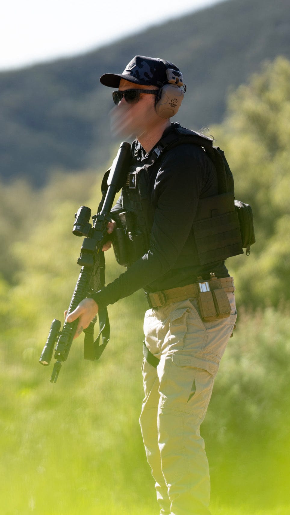 Man carrying a rifle while wearing Alpha Geir tactical gear—rugged, high-performance apparel built for durability in the field.
